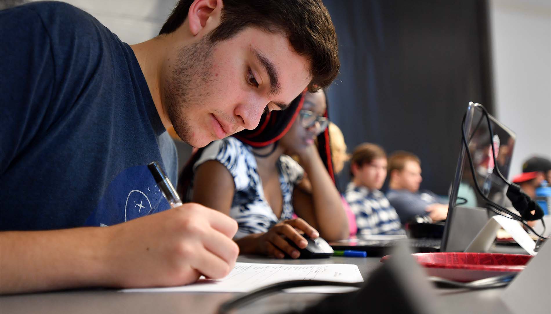 male student writing notes in class